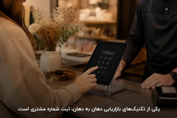 دست شخصی در حال ثبت شماره مشتری در تبلت در فضای داخلی فروشگاه با نور گرم