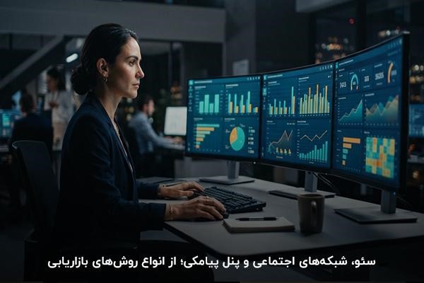 زنی با لباس تیره در حال کار با موس و سه مانیتور روشن در مقابل او