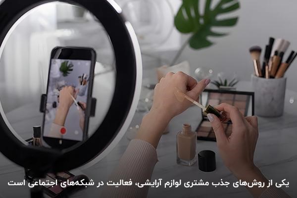 تصویری از نمای نزدیک دست شخصی در حال تست کرمپودر در حال فیلمبرداری با موبایل و رینگلایت